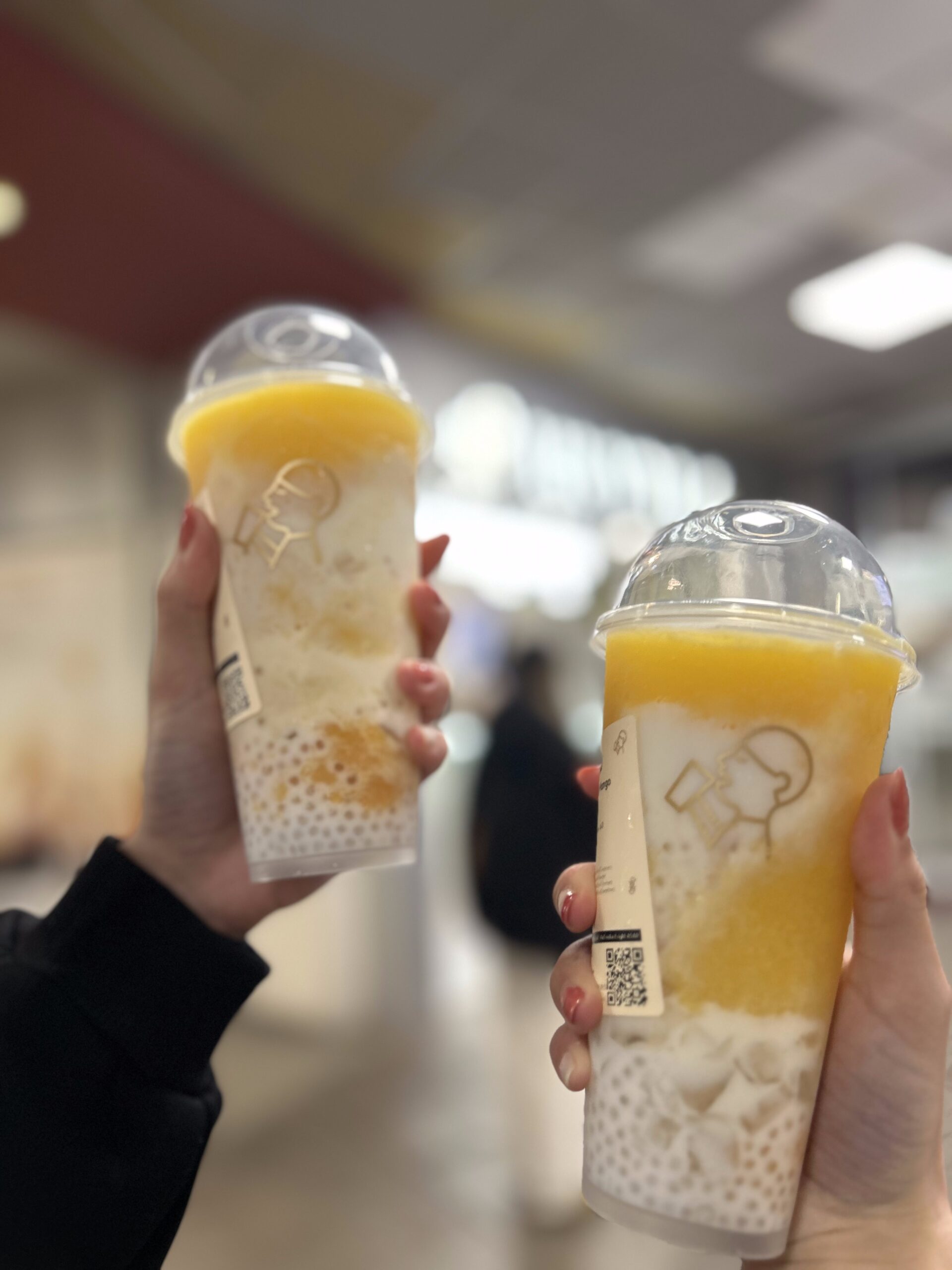 Two hands holding up Mango Sago Coconut Drink